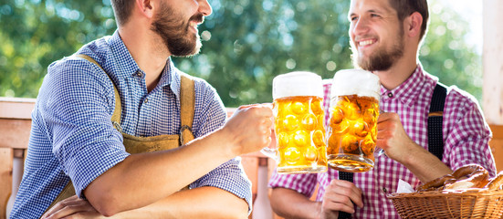 Men in traditional bavarian clothes holding mugs of beer