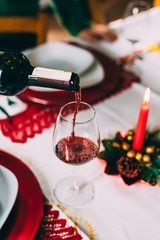 Close up on a bottle of red wine pouring a glass on a christmas table - christmas new year's eve, celebration concept