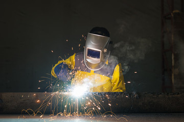 Industrial welder in manufacturing plant welding to finish a pipeline - obrazy, fototapety, plakaty