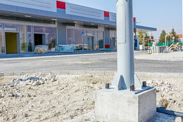 Concrete base of street lamp pole, tube metal lamppost