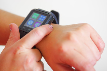Closeup arm wrist wearing smart watch, screen lit up, using other hand pressing on device, white studio background