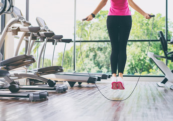 Fitness concept. Healthy lifestyle. Young slim woman jumping with skipping rope in gym. - Powered by Adobe