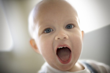 Portrait of a toddler eating cake in a house.