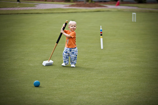 Male toddler attempting to play croquet