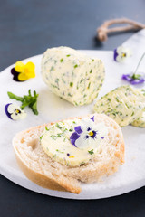 Sandwich with herb and edible flowers butter on marble cutting board. Healthy food.