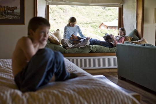 Two teenage relaxing in a room with their younger brother.