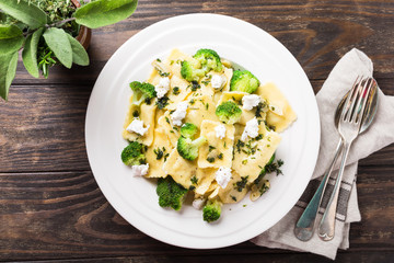 Italian ravioli with goat cheese, broccoli and herbs on old wooden background. Healthy food. Top view. Copy space.