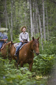 Father and son horseriding through forest