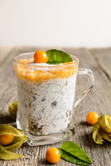 Probiotic yogurt with chia seeds, coconut, honey and physalis puree in a glass jar