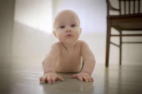 Portrait of a shirtless young baby boy lying on his stomach.