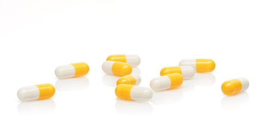 Pile of yellow and white capsules isolated on white background