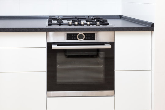 Build-on Oven And Hob In White Kitchen With Black Counter, Close Up. 