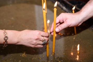Woman hand lighting candles in a church.
