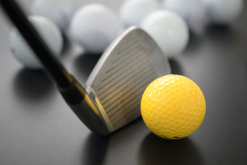 white and one yellow golf balls on black floor. individuality an