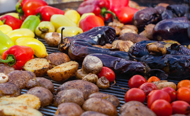 Red yellow green bell peppers potatoes mushrooms tomatoes and eggplant grilled until golden brown. The concept of proper nutrition and a healthy lifestyle. Cooking vegetables on the barbecue.