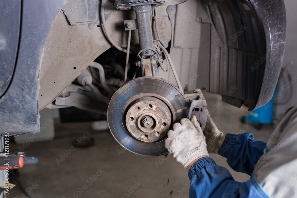 Wall mural change the old drive to the brand new brake disc on car in a garage. auto mechanic repairing .