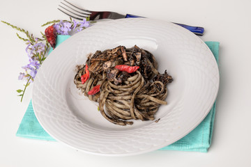 Linguine with squid ink and red pepper flakes on a white background