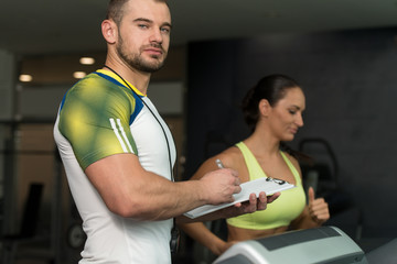 Personal Trainer And client In Gym On Treadmills
