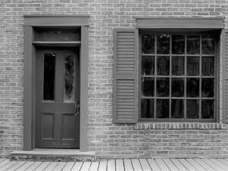 Dilapidated old brick building with door and window, and wooden sidewalk in front