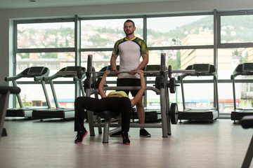 Woman Train Chest On Bench With Personal Trainer