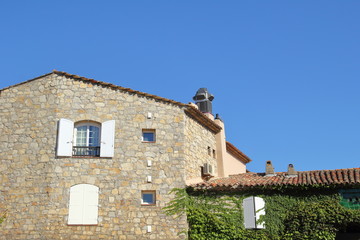 Pretty stone Provencal cottage with copy space and bright blue sky, with traditional shutters