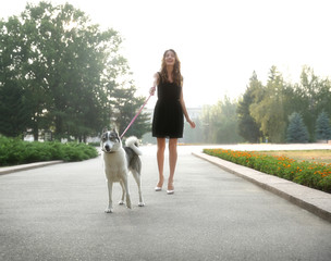 Naklejka na ściany i meble Young beautiful woman walking with dog outside