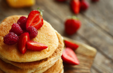 Tasty pancakes with fresh berries on cutting board