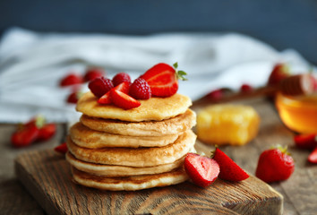 Tasty pancakes with fresh berries on cutting board