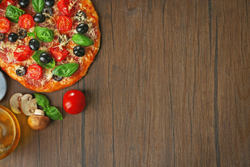 Tasty pizza with vegetables, herbs and oil on wooden background