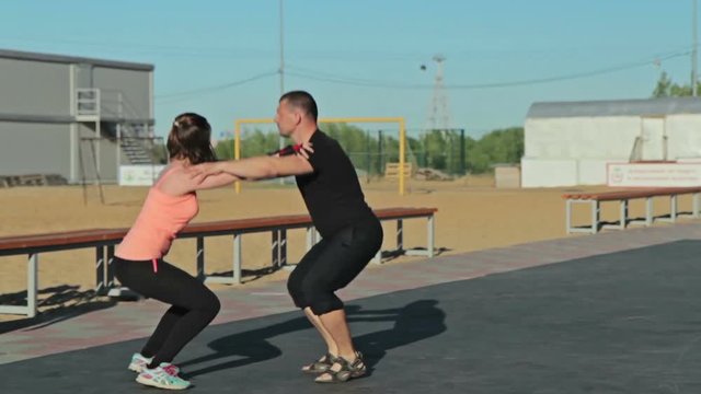 Man and girl squatting together, crossfit workout