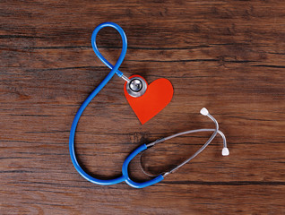 Stethoscope and red heart on wooden table