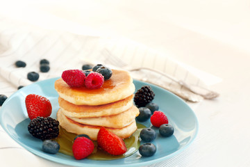 Delicious pancakes with berries and honey on blue plate