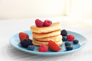 Plate with delicious pancakes and berries on table, closeup
