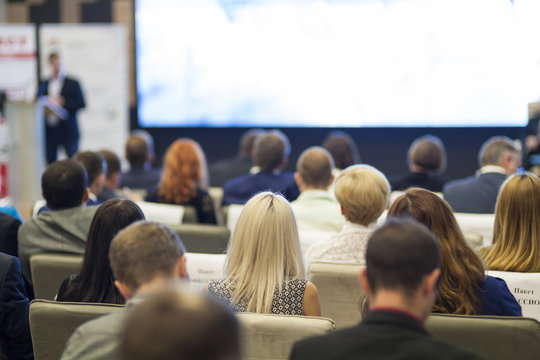 Business Ideas and Concepts. Group of Business People Sitting in Congress Hall and Listening to Host on Stage