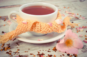 Vintage photo, Cup of tea with wild rose flower on old rustic wooden background