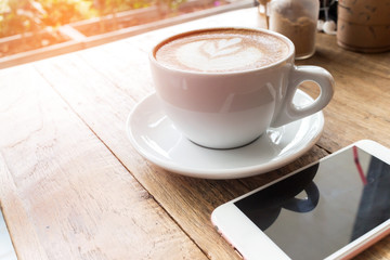 Cup of coffee and smart phone on wooden table