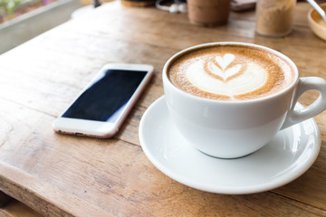 Cup of coffee and smart phone on wooden table