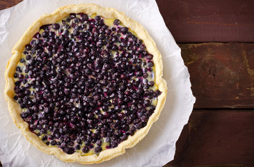Bilberry, blueberry tart with lavender on white plate, wooden background