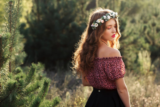 Beautiful girl standing in forest half-turned. Nymph posing near pine-trees. Beauty, nature, relaxation, conservancy, ecology concept