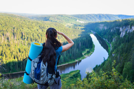 Hiker with backpack standing on a rock and looking to somewhere far away