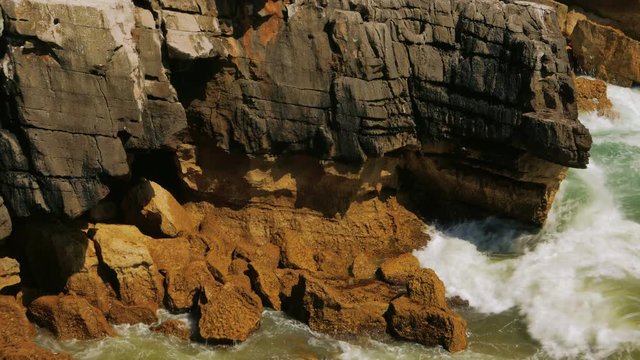 Closeup slow motion view of sea waves pounding against rocks
