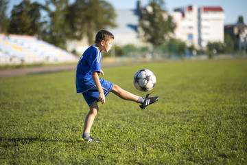 Boy kicking soccer ball on the football field