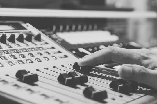 sound engineer hands on digital music studio mixer for DJ / recording / radio / tv broadcast concept. black & white film filter