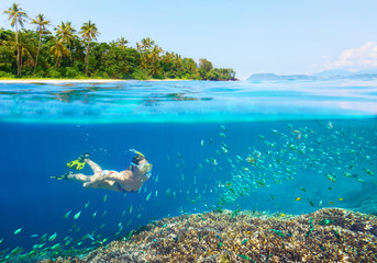Woman snorkeling in clear tropical waters. - obrazy, fototapety, plakaty