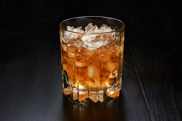 Glass of whiskey with crushed ice on dark wooden background