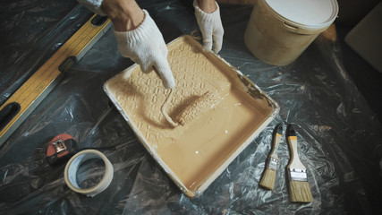 Worker picking a paint roller on a special tray.