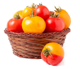 red and yellow tomatoes in a wicker basket isolated on white background