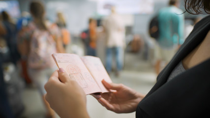 A young woman is looking at her visa in the passport