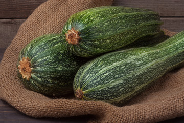 green zucchini on sackcloth and wooden background