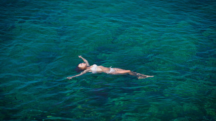 Young woman swimming in beautiful azure sea